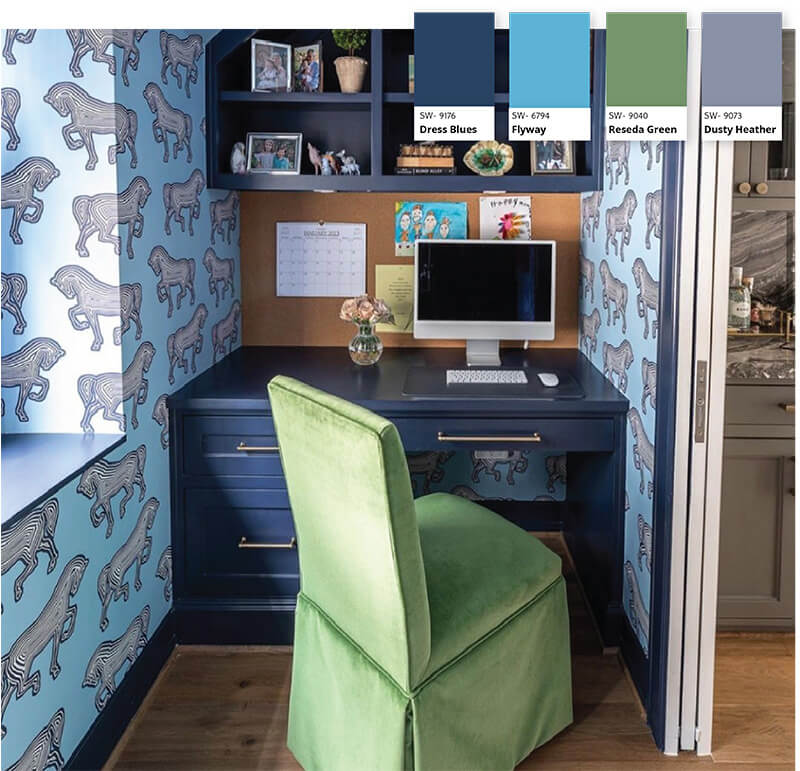 A small office space with blue wallpaper containing zebras and a dark blue desk